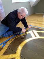 Gary, applies the clear coat to the 23K Gold Leaf on the Fair Harbor Fire Dept.  Maltese Cross logo on the floor of the meeting room